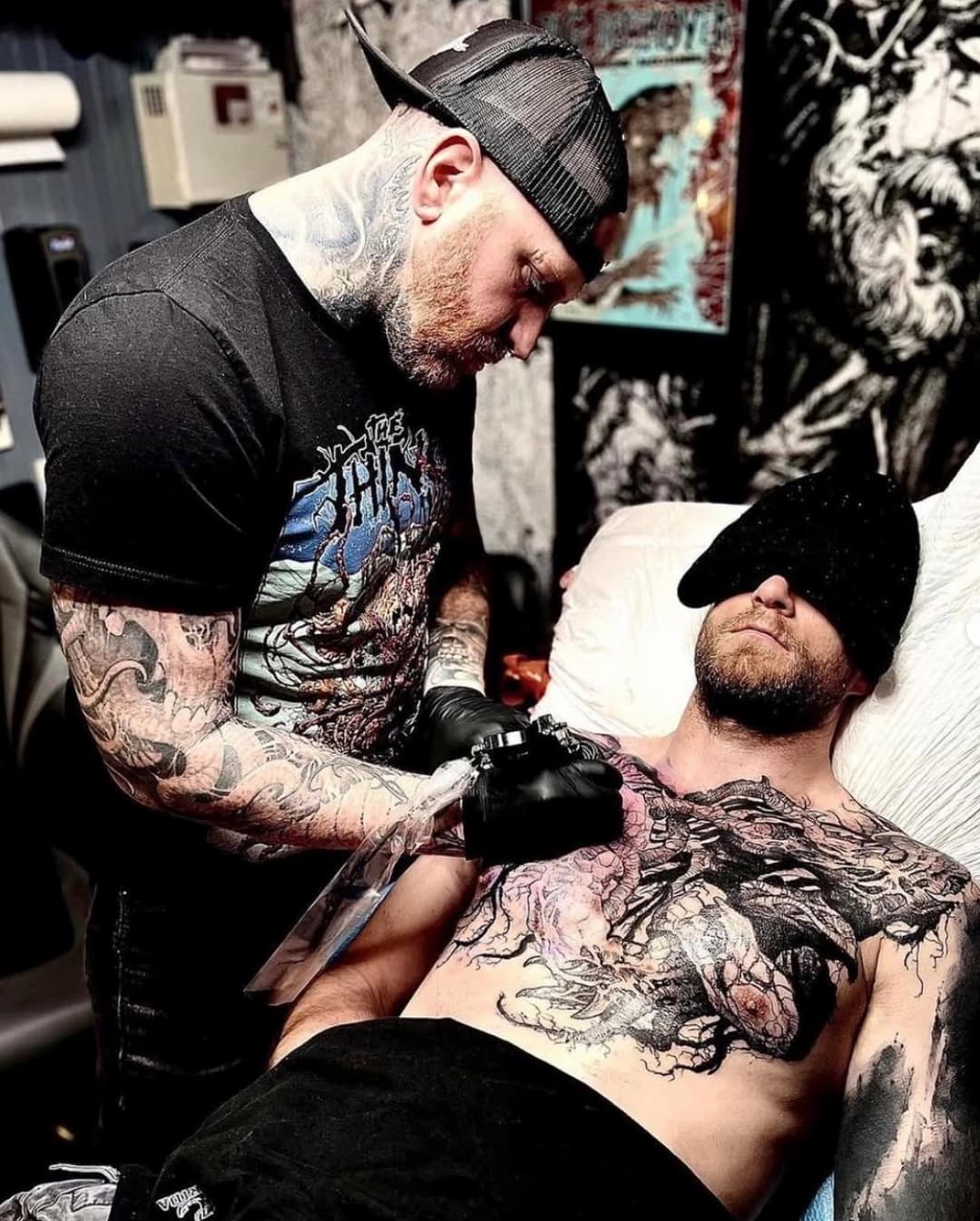 A tattooer working on a large blackwork chest piece at Tomb Gallery
